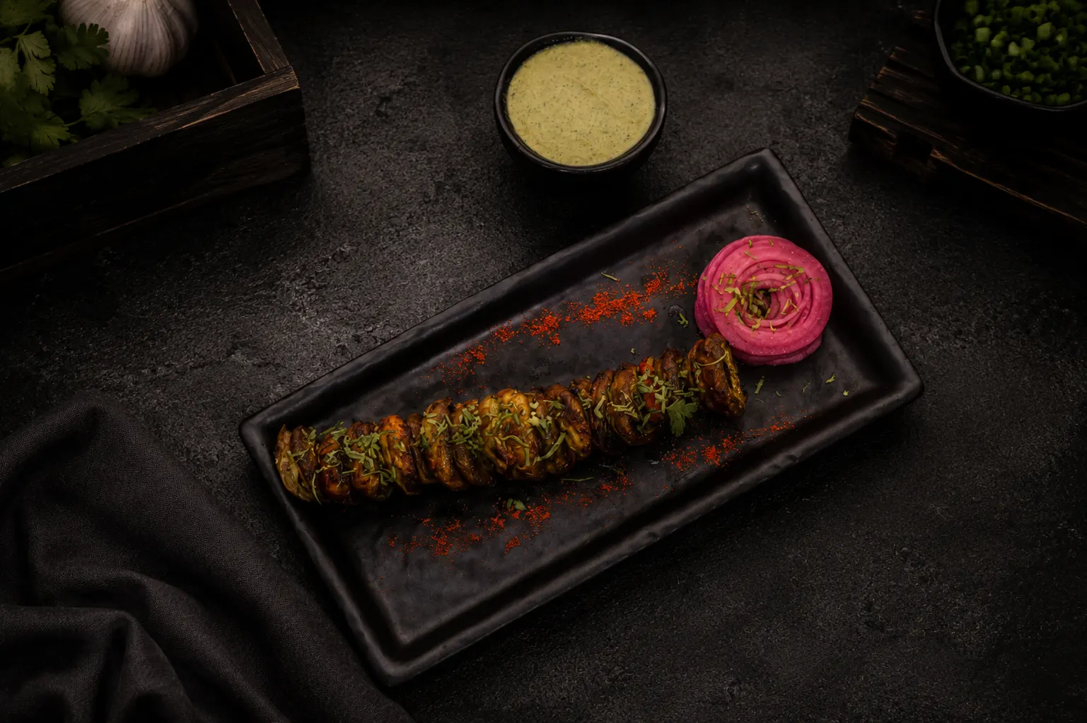 Mushroom tikka arranged on a dark rectangular plate with dipping sauce